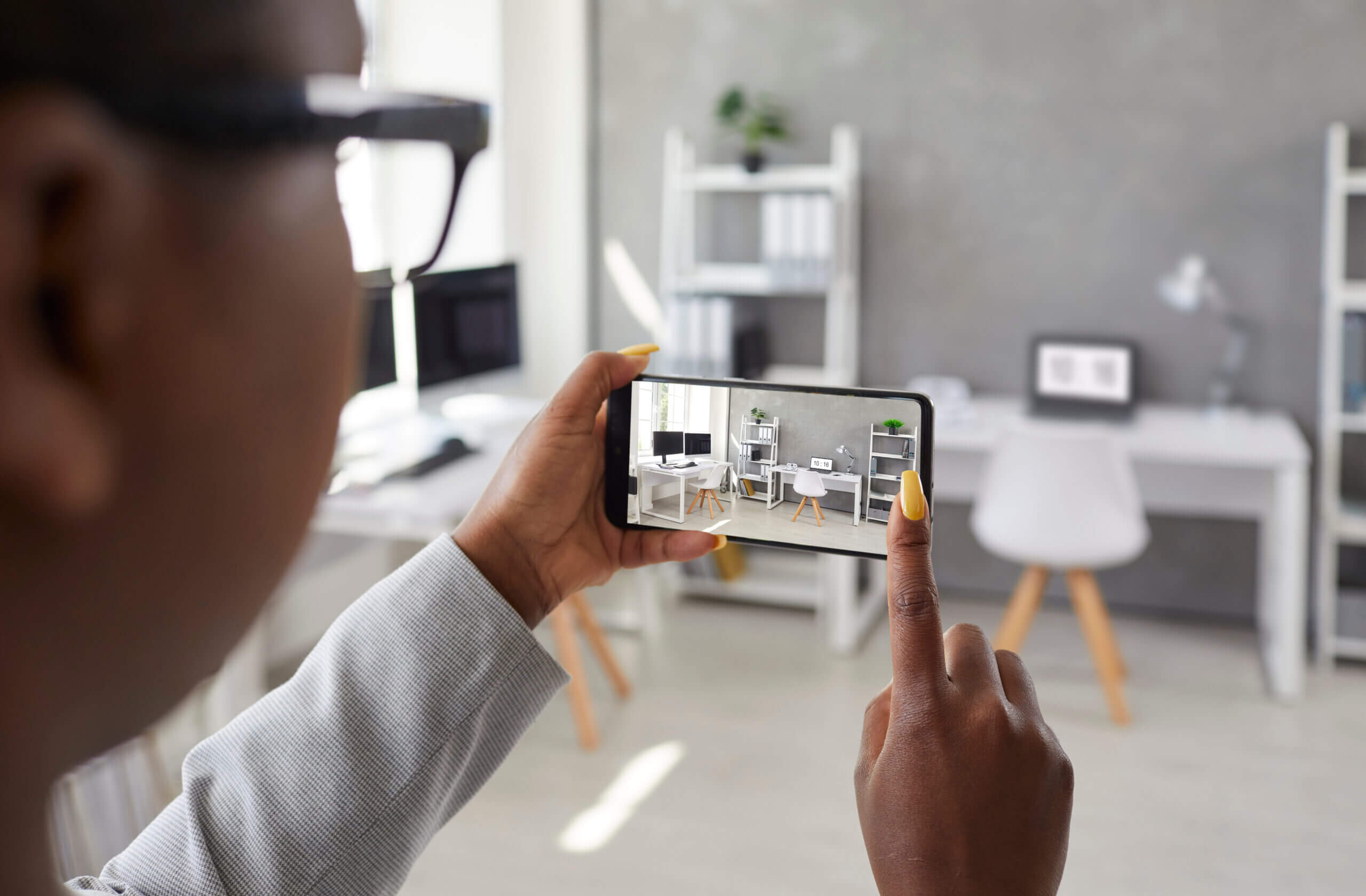 Woman holding mobile phone and taking photo of interior in office or apartment for rent